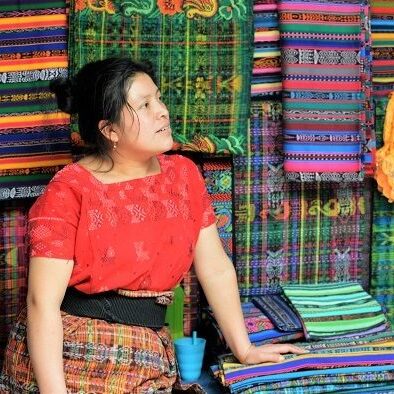 Woman in Guatemala standing in front of colorful linens 
